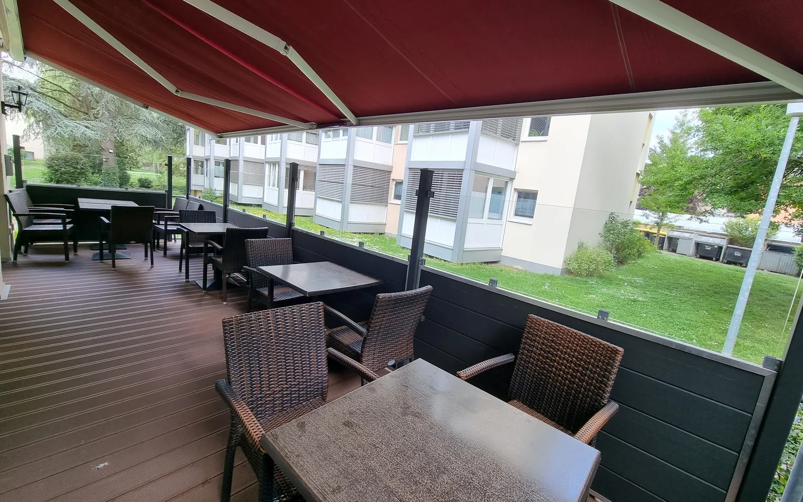 Sommerterrasse des Restaurants unter bordeauxroter Markise
